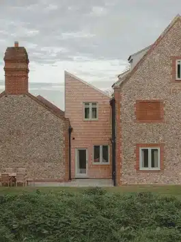 The cedar shingle cladding of the extension situated between the existing masses of the house. Alexander Hills Architects